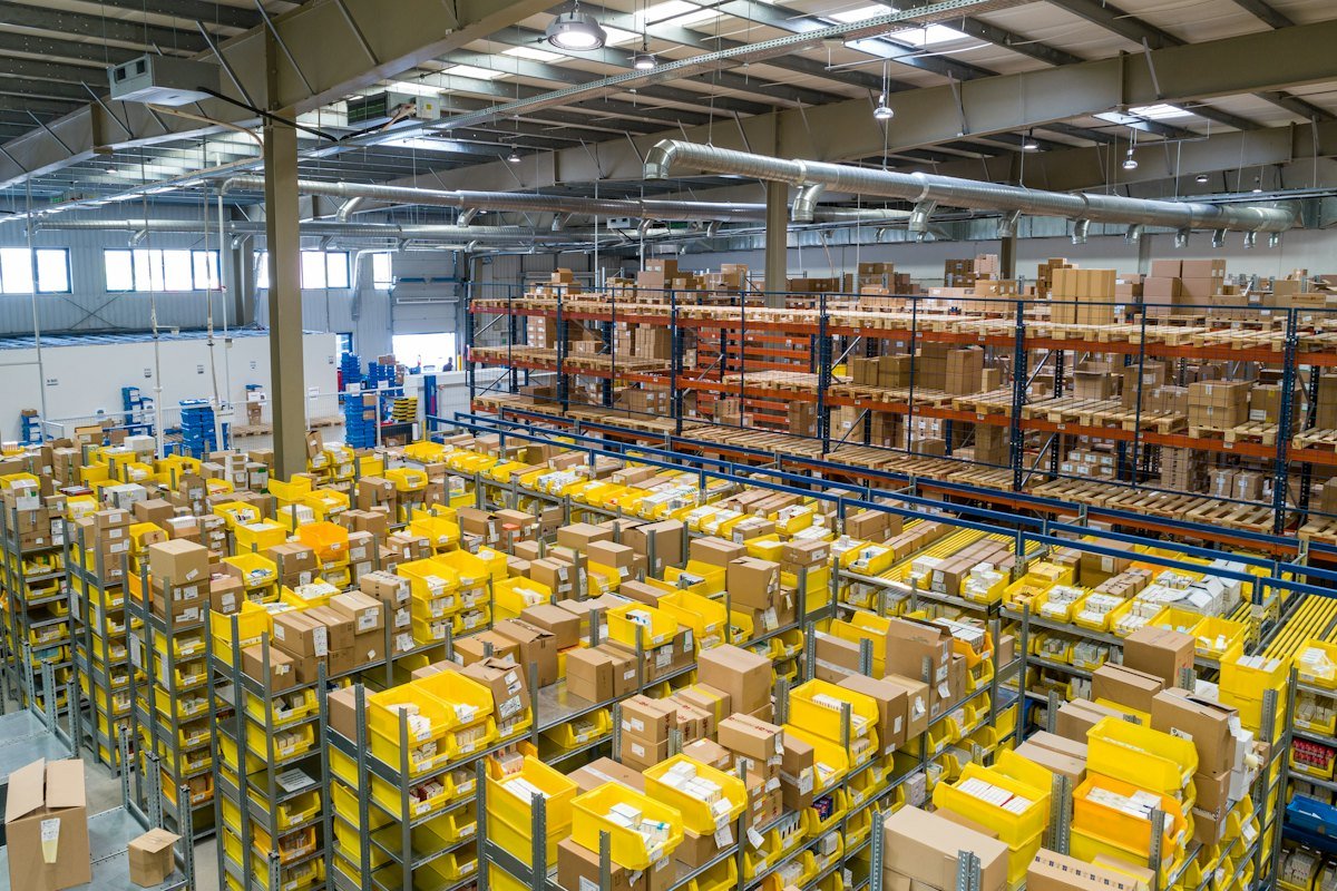 Large modern warehouse with yellow racking stacked with cardboard boxes and pallets